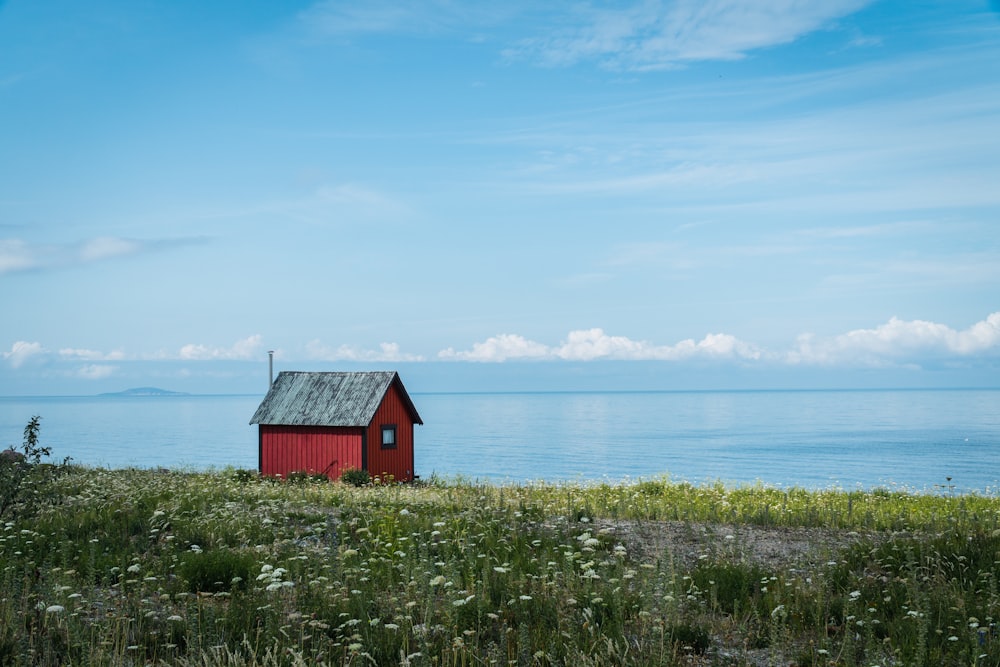 Maison en bois rouge près d’un plan d’eau pendant la journée