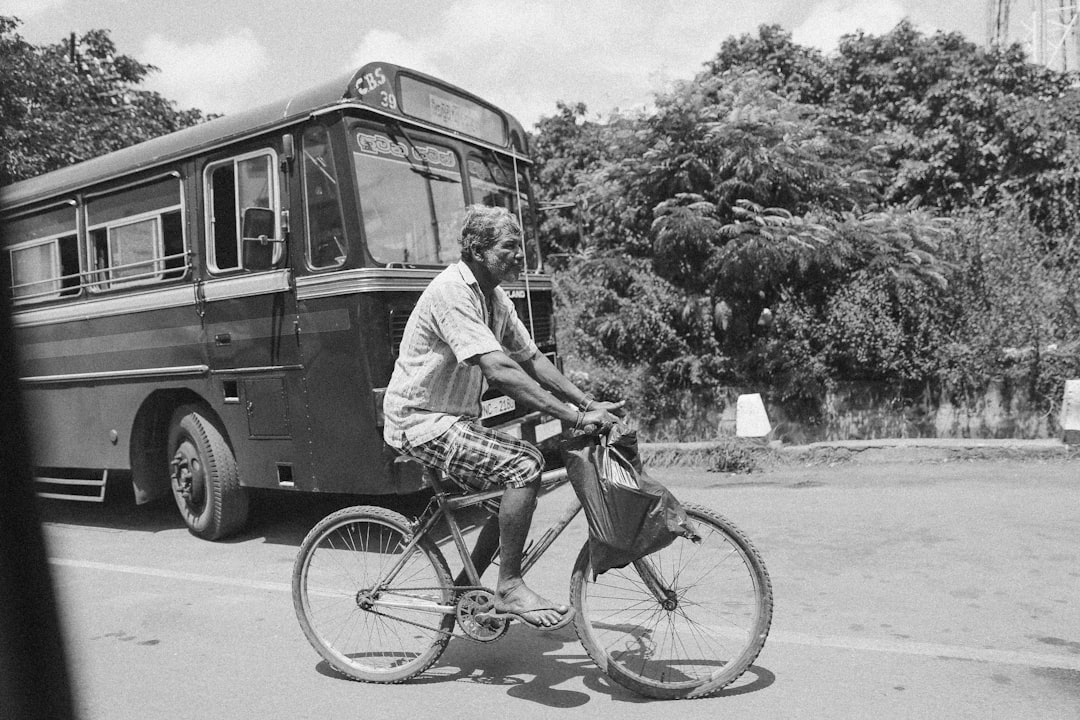 man in white dress shirt riding on bicycle in grayscale photography