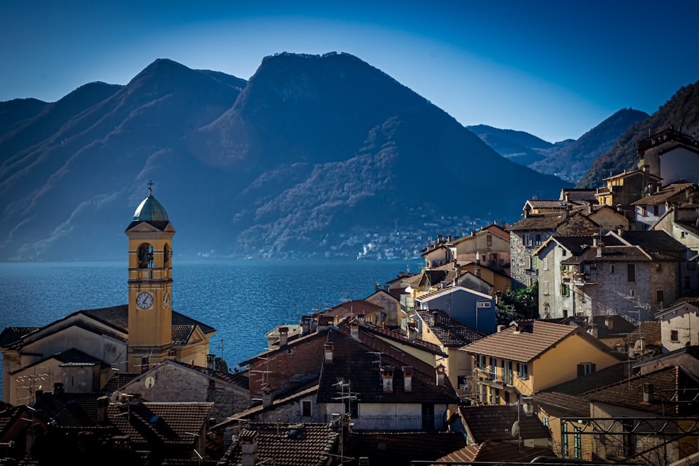 edifici in cemento marrone e bianco vicino a specchio d'acqua e montagna durante il giorno