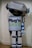 A humanoid robot costume with a metallic gray and blue color scheme, boxy limbs, and a large rectangular torso. The robot has a large head with circular antenna on top and large, round blue eyes. The front of the torso features the text 'Plug'n SAVE' in bold letters.
