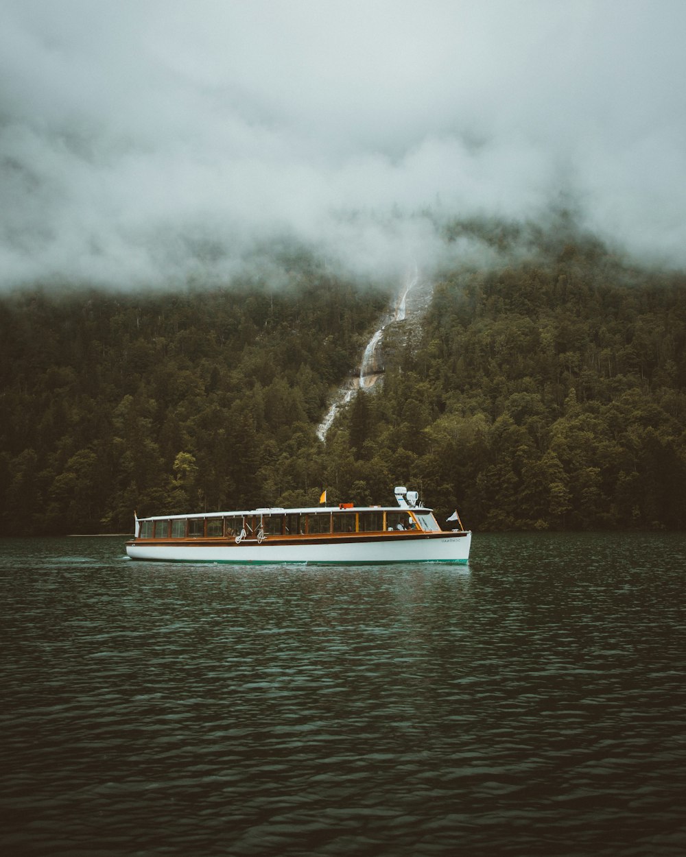 white and blue boat on water under white clouds