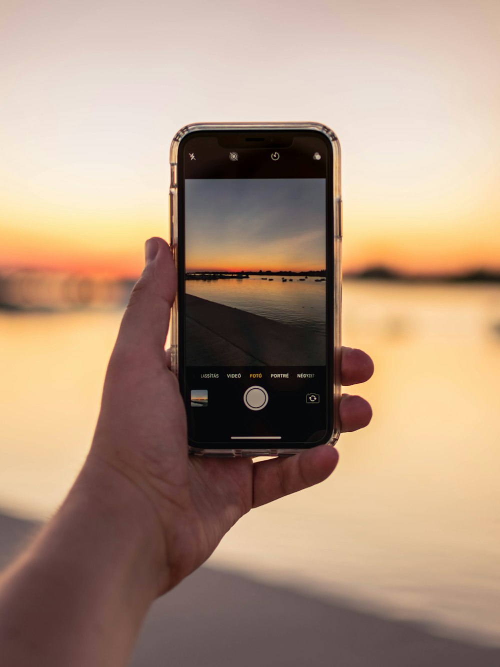 Person, die das iPhone hält, fotografiert den Sonnenuntergang