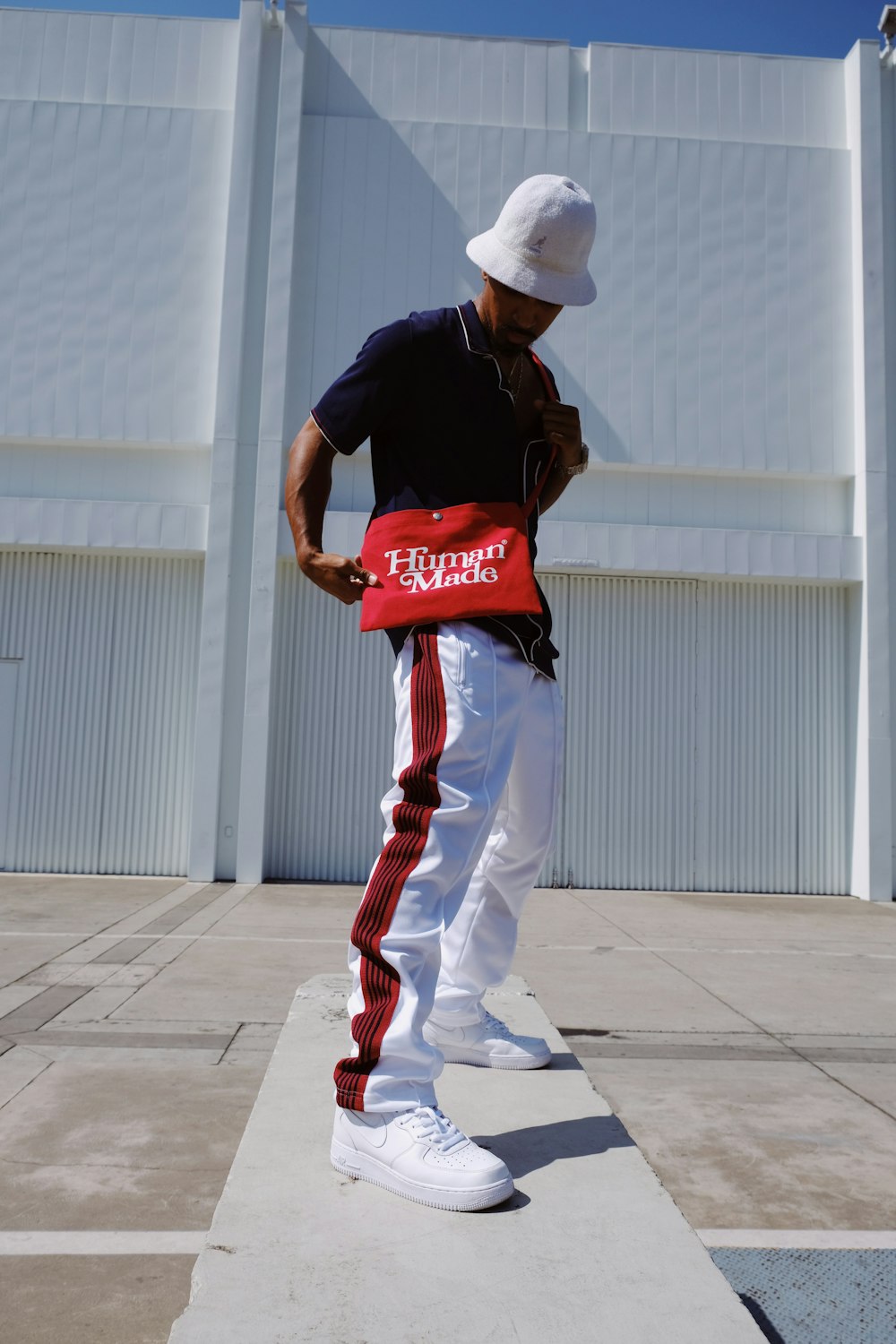 Hombre con camiseta roja y blanca con cuello redondo y pantalón blanco