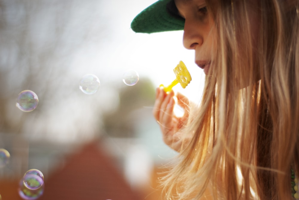 woman in green hat blowing bubbles