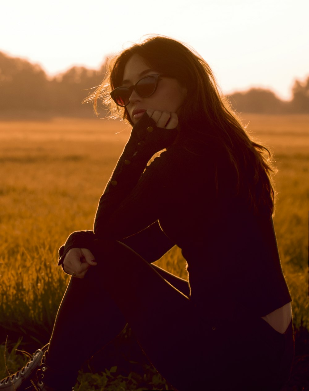 woman in black long sleeve shirt and black sunglasses standing on green grass field during daytime