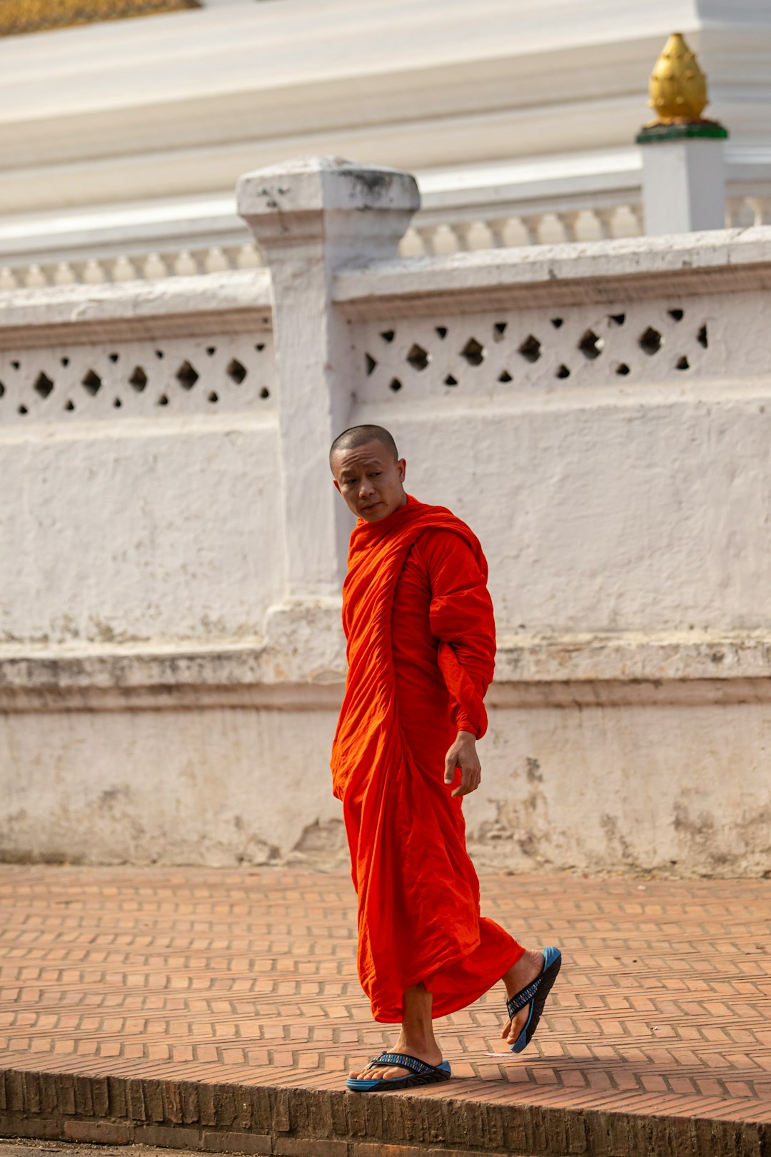 man in red thobe sitting on brown concrete floor during daytime