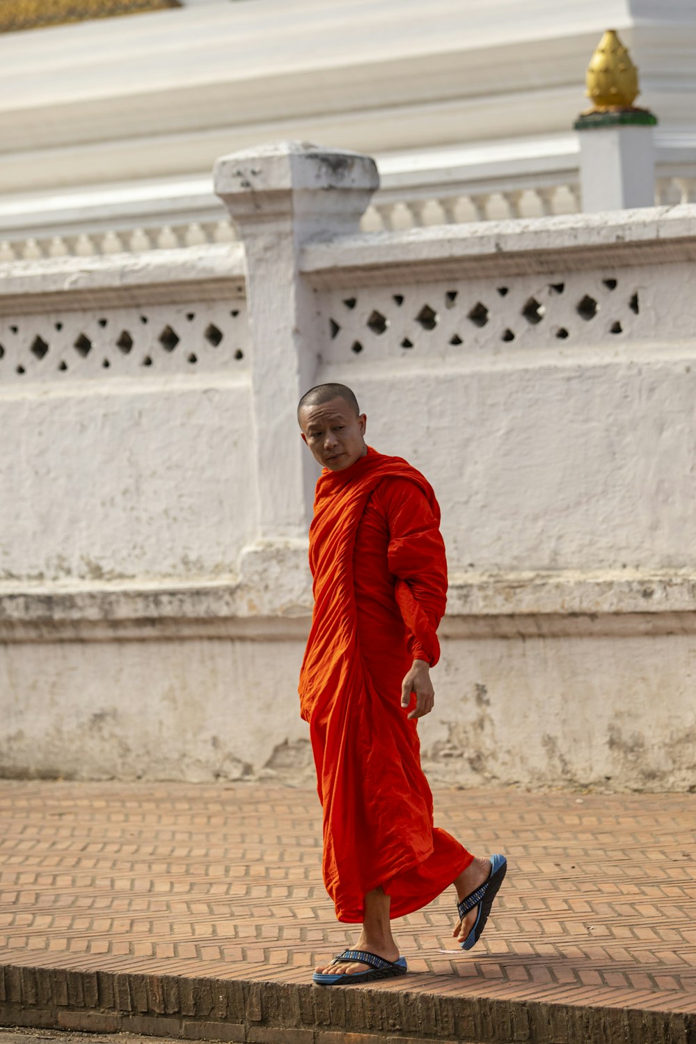 man in red thobe sitting on brown concrete floor during daytime