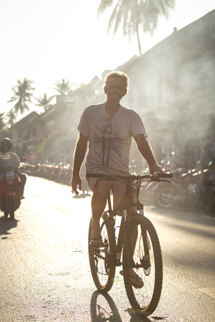 A rider cruising past palm trees on a sunny Marrakech street with the Atlas Mountains in the background.