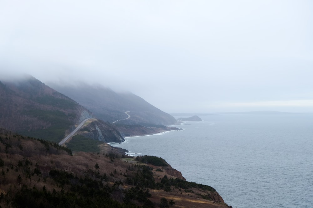 green and brown mountain beside sea during daytime