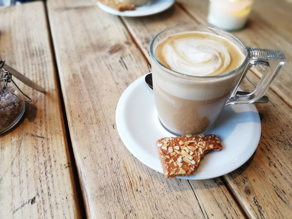 weiße Keramiktasse mit Cappuccino auf weißer Keramikuntertasse