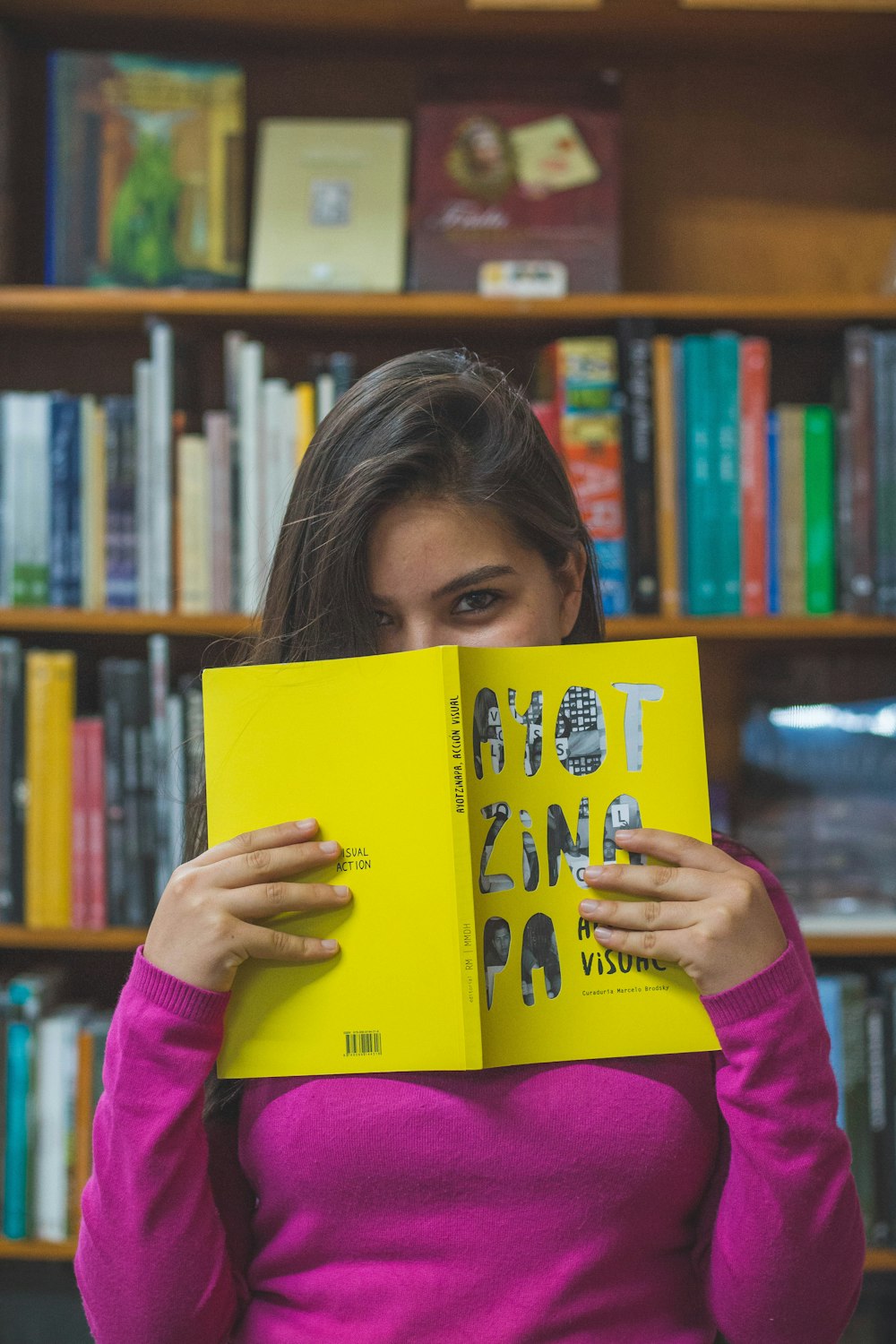 woman in purple long sleeve shirt holding yellow book