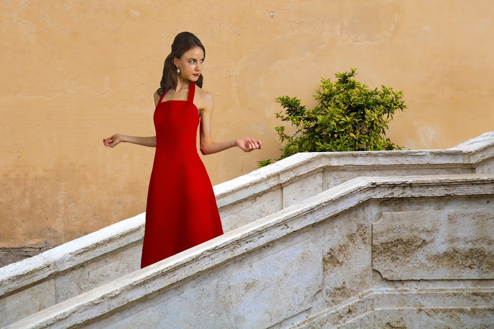 woman in red sleeveless dress standing on stairs