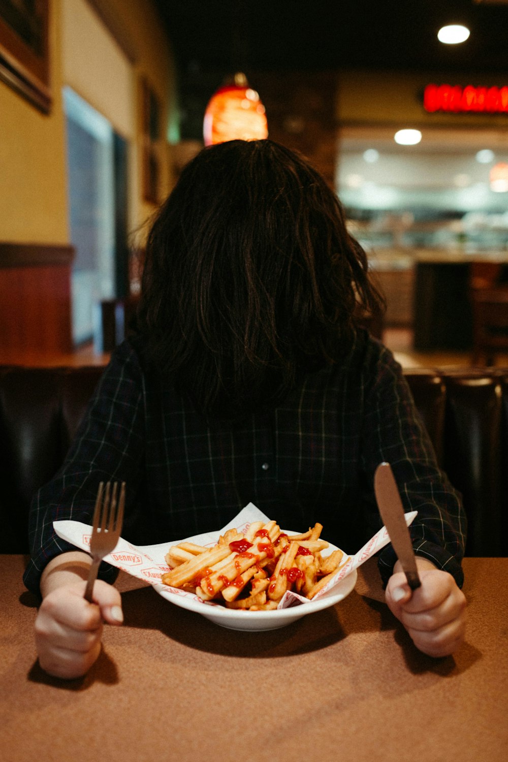 woman in black and white plaid long sleeve shirt eating fries