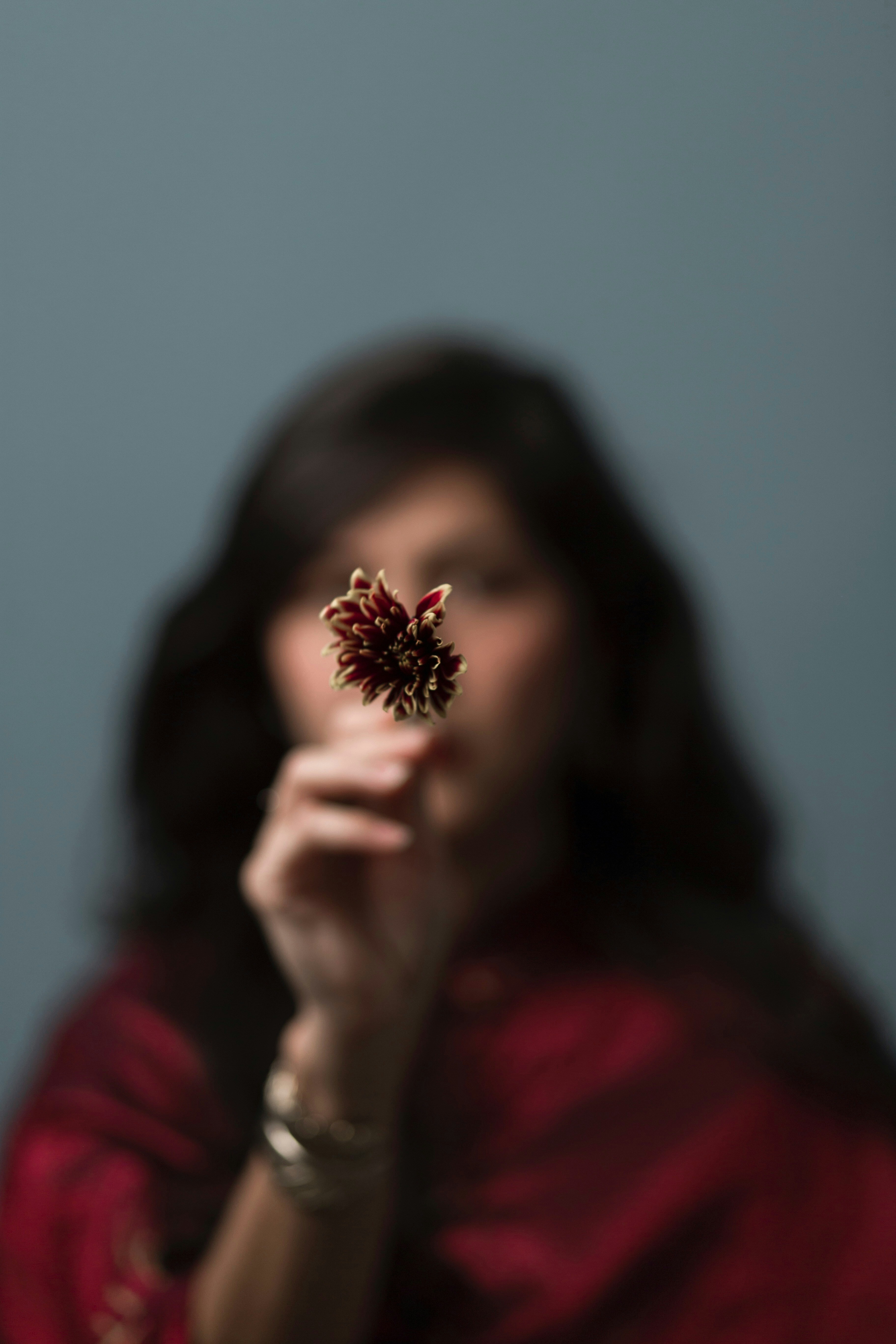 woman in red long sleeve shirt holding brown flower