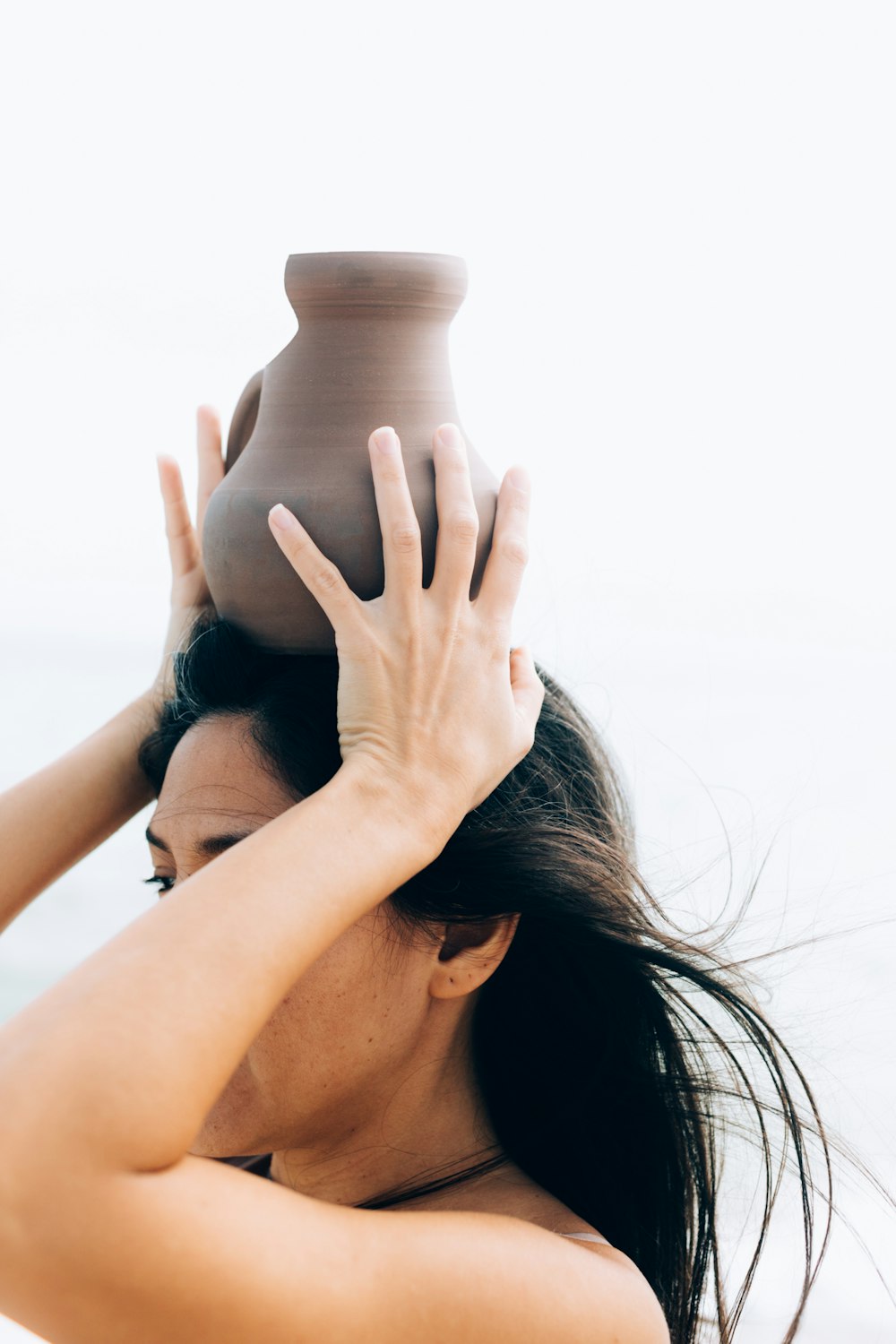 woman in black tank top covering her face with her hands