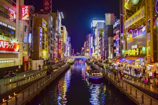 boat on river between high rise buildings during nighttime