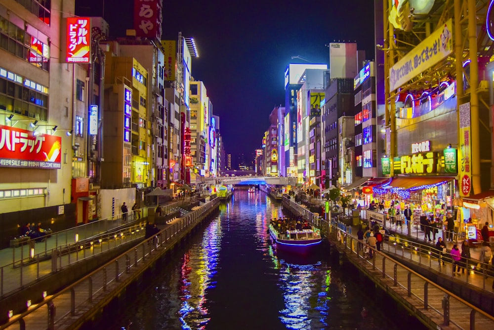 boat on river between high rise buildings during nighttime