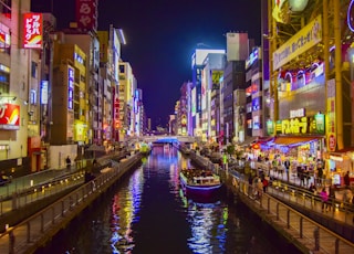 boat on river between high rise buildings during nighttime