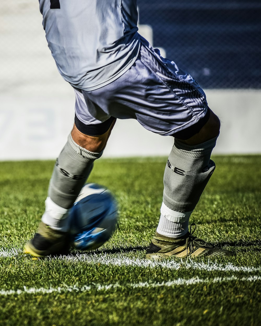 man in white soccer jersey kicking soccer ball on green grass field during daytime