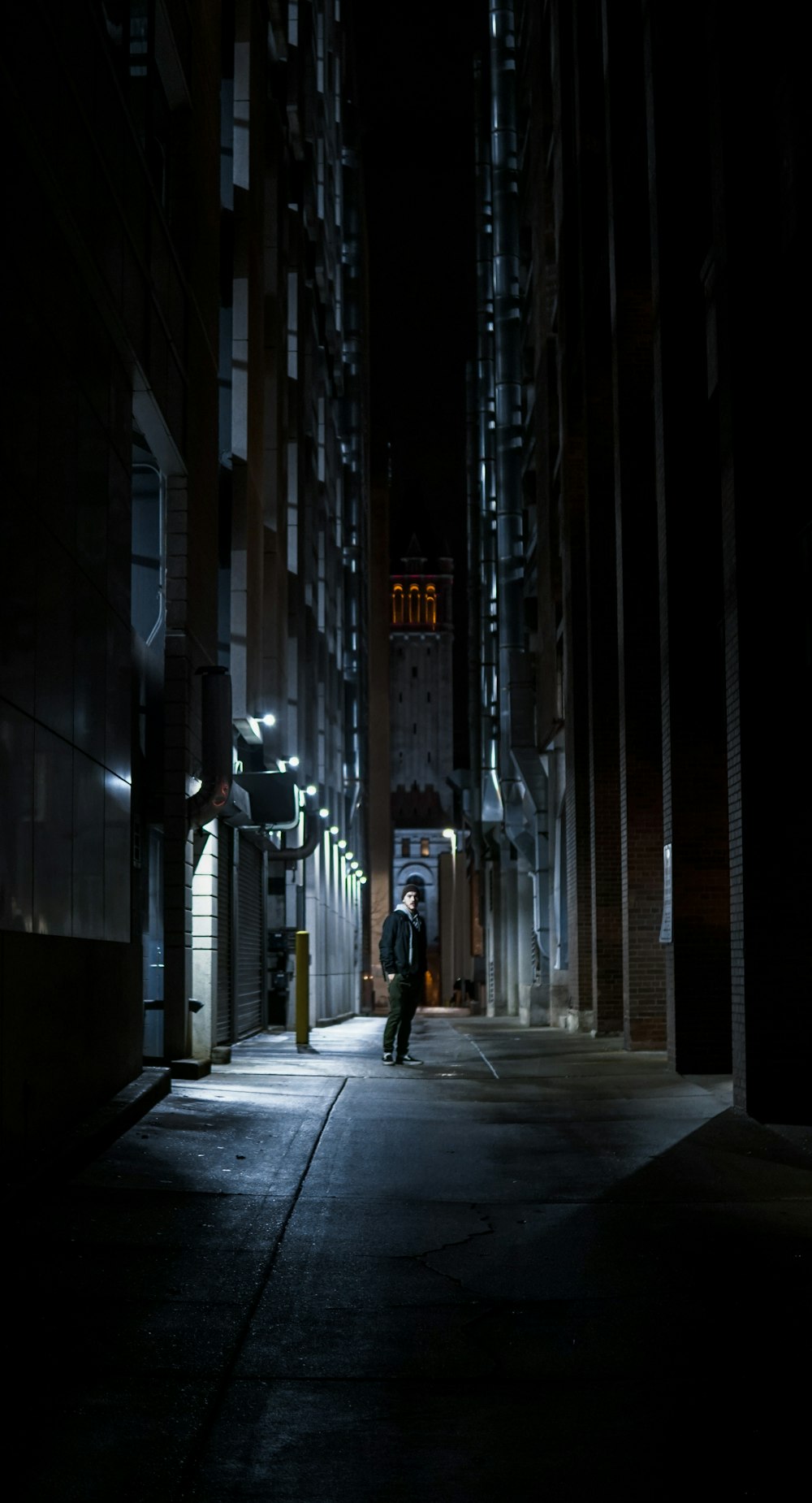 man in black jacket walking on street during nighttime