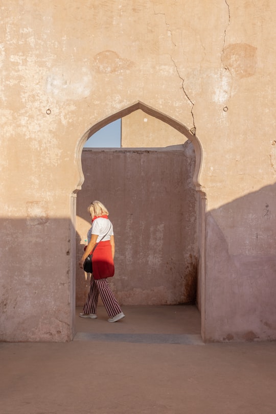 woman in white long sleeve shirt and red skirt standing on gray concrete floor during daytime in Rajasthan India