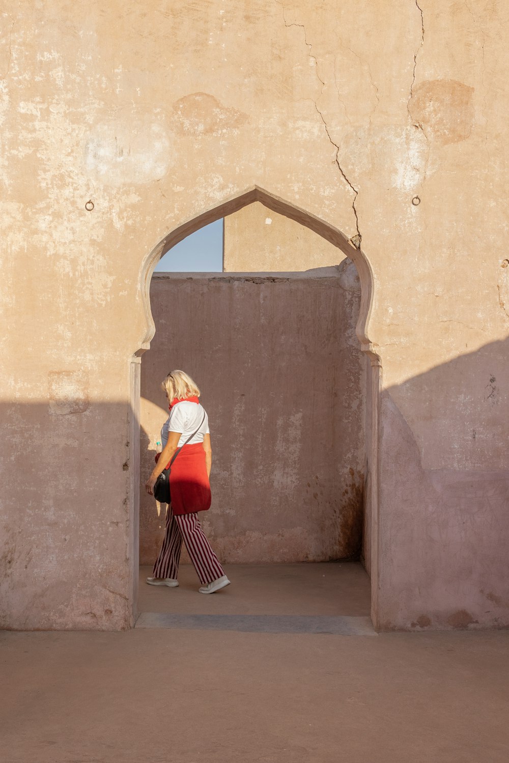 woman in white long sleeve shirt and red skirt standing on gray concrete floor during daytime