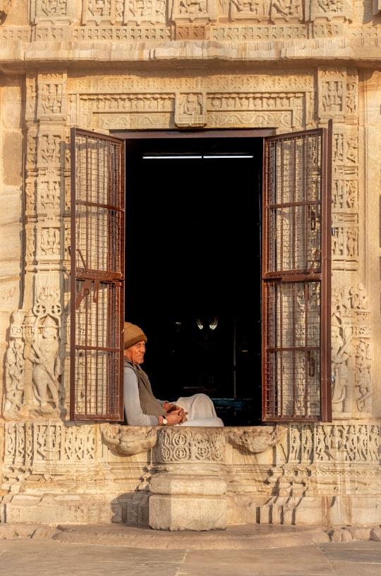man in white thobe sitting on white chair near brown wooden door in Rajasthan India