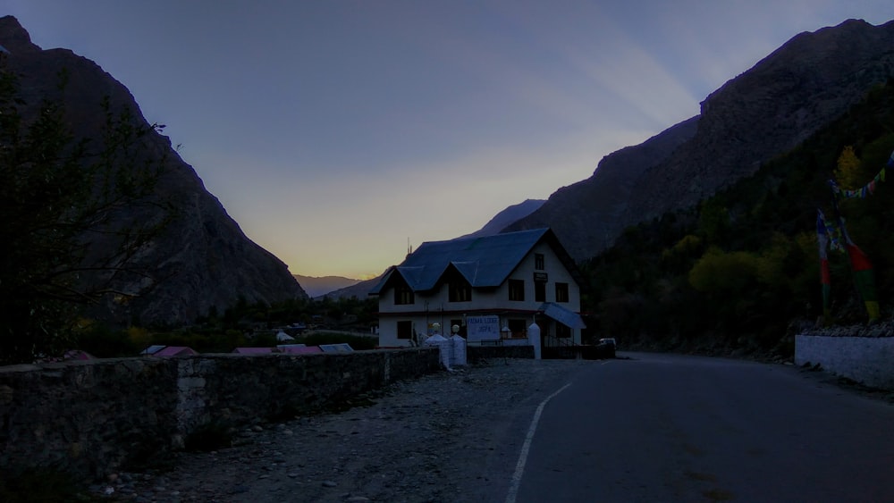 a house on the side of a road with mountains in the background