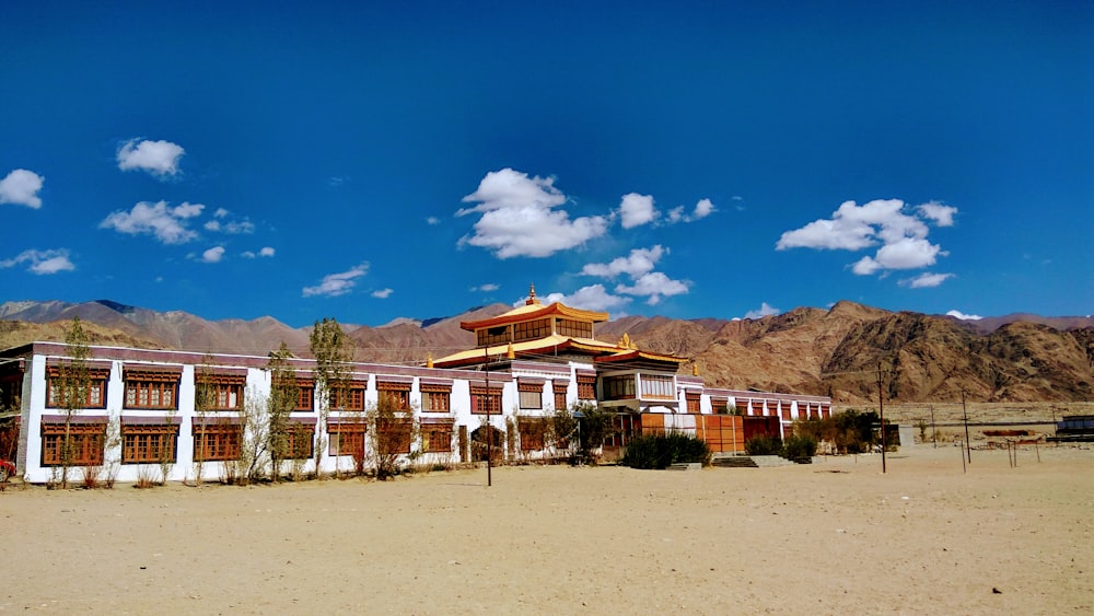 a building in the middle of a desert with mountains in the background