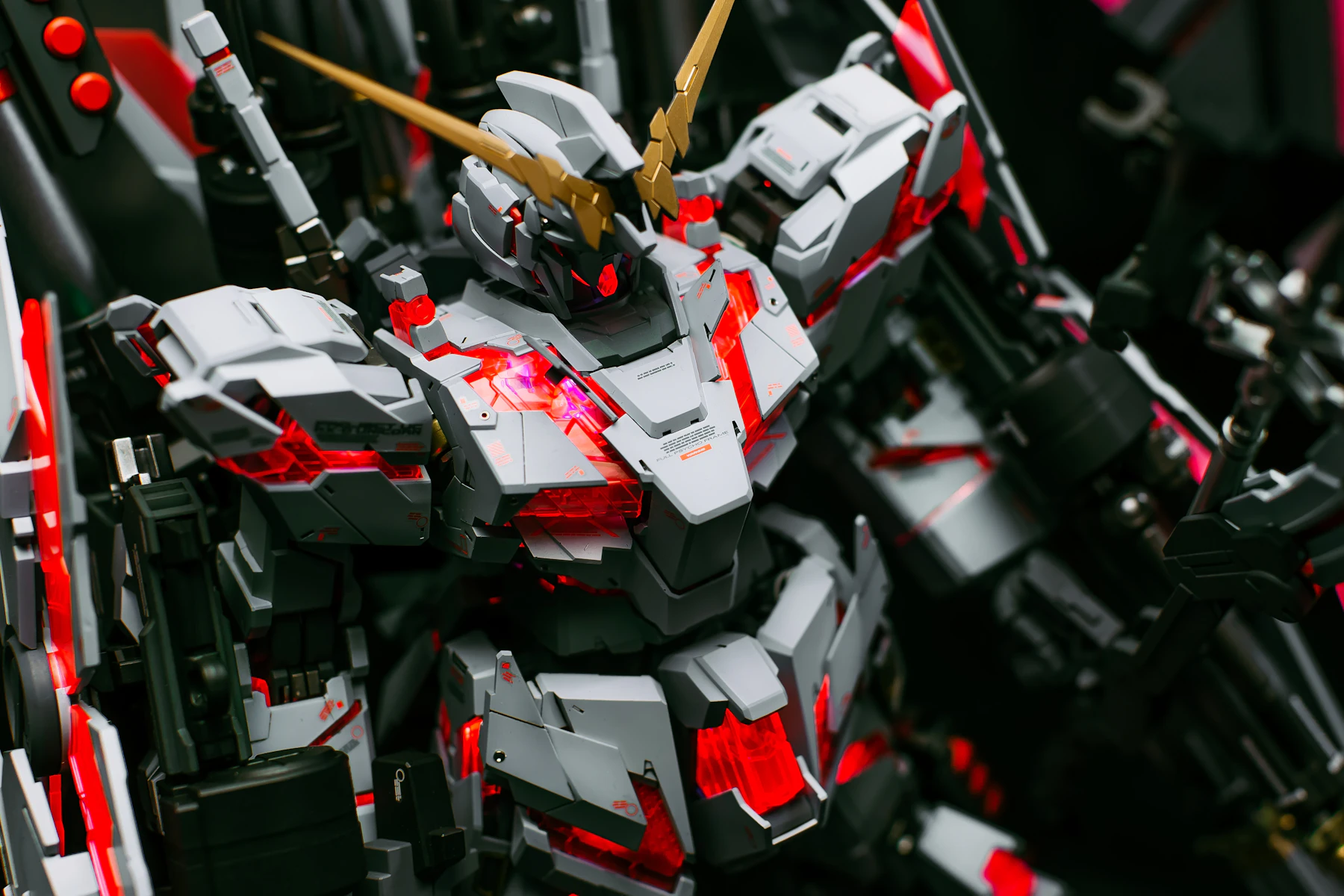 Close-up of a white and red robot model with a gold V-shaped crest, surrounded by black armor parts