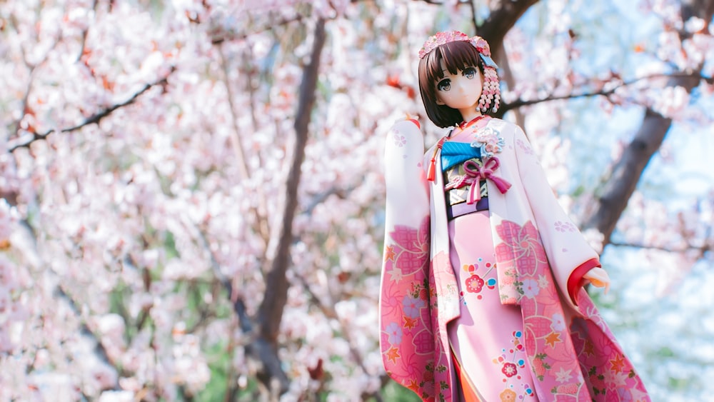 woman in white and pink floral kimono standing near trees during daytime