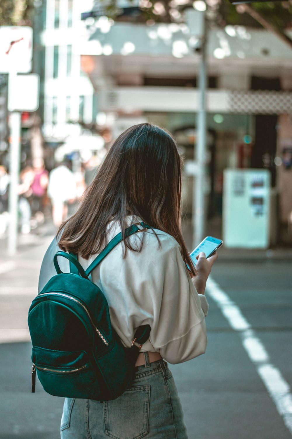 Femme en manteau beige tenant un smartphone bleu