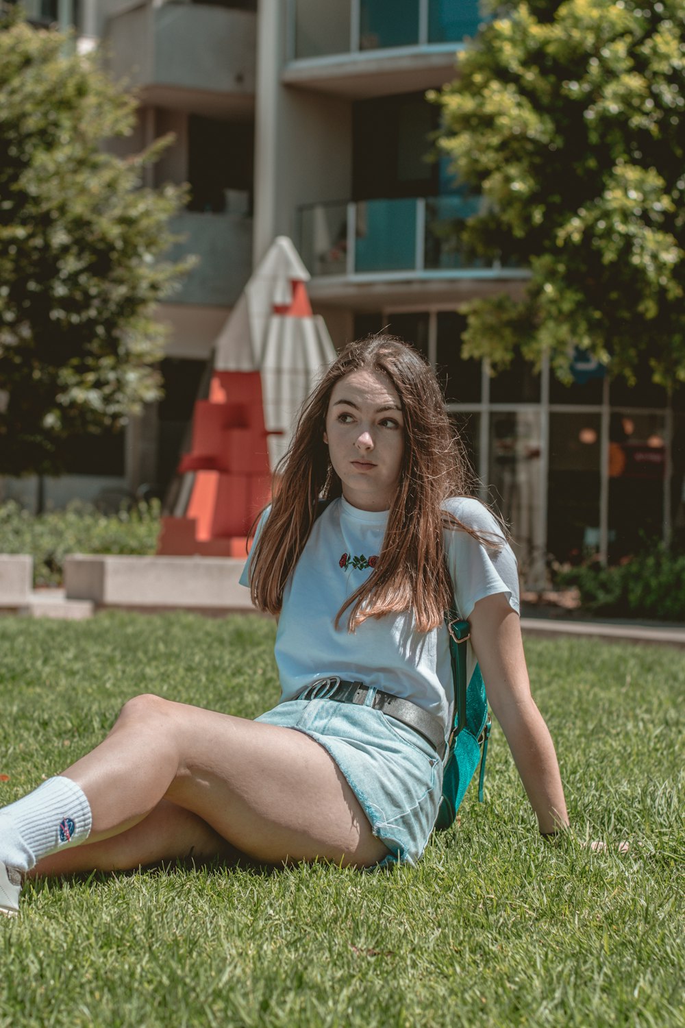 woman in blue and white t-shirt sitting on green grass field during daytime