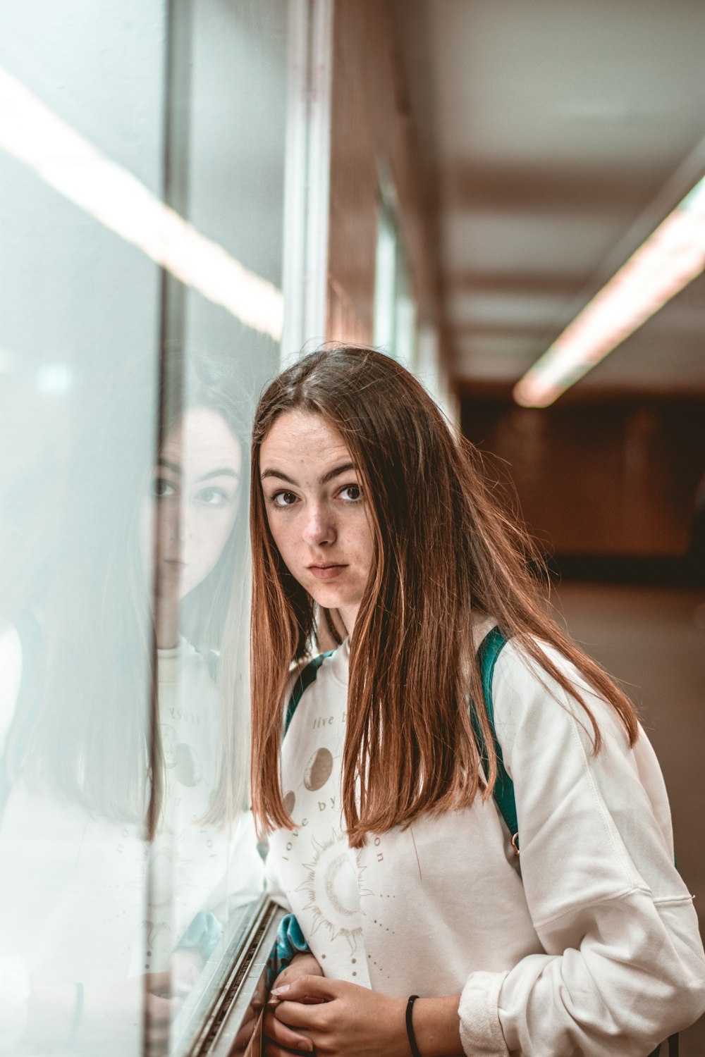 woman in white coat standing near glass window