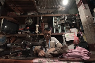 Technician repairing an industrial sewing machine in a workshop setting.