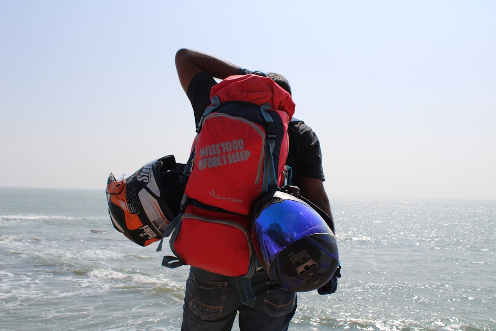 man in red and black backpack and blue denim jeans carrying red and black backpack