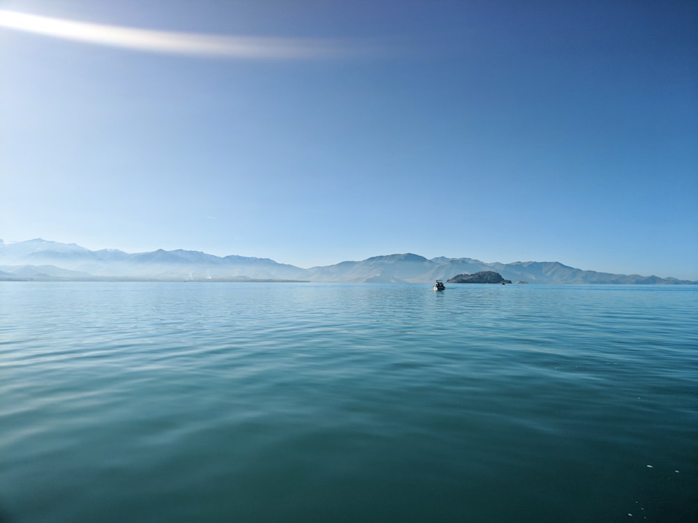 body of water near mountain under blue sky during daytime