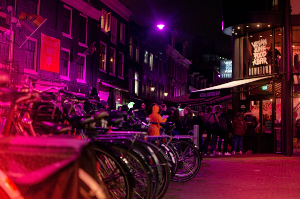 Evening scene with the beer bike lit up by warm lights, surrounded by happy riders raising their glasses.