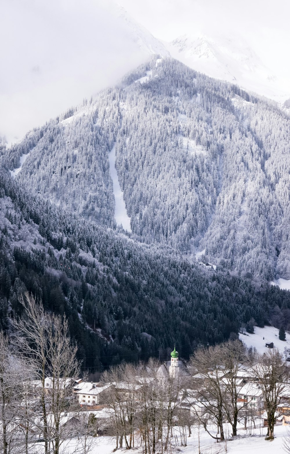 pessoa em pé no chão coberto de neve perto da montanha durante o dia
