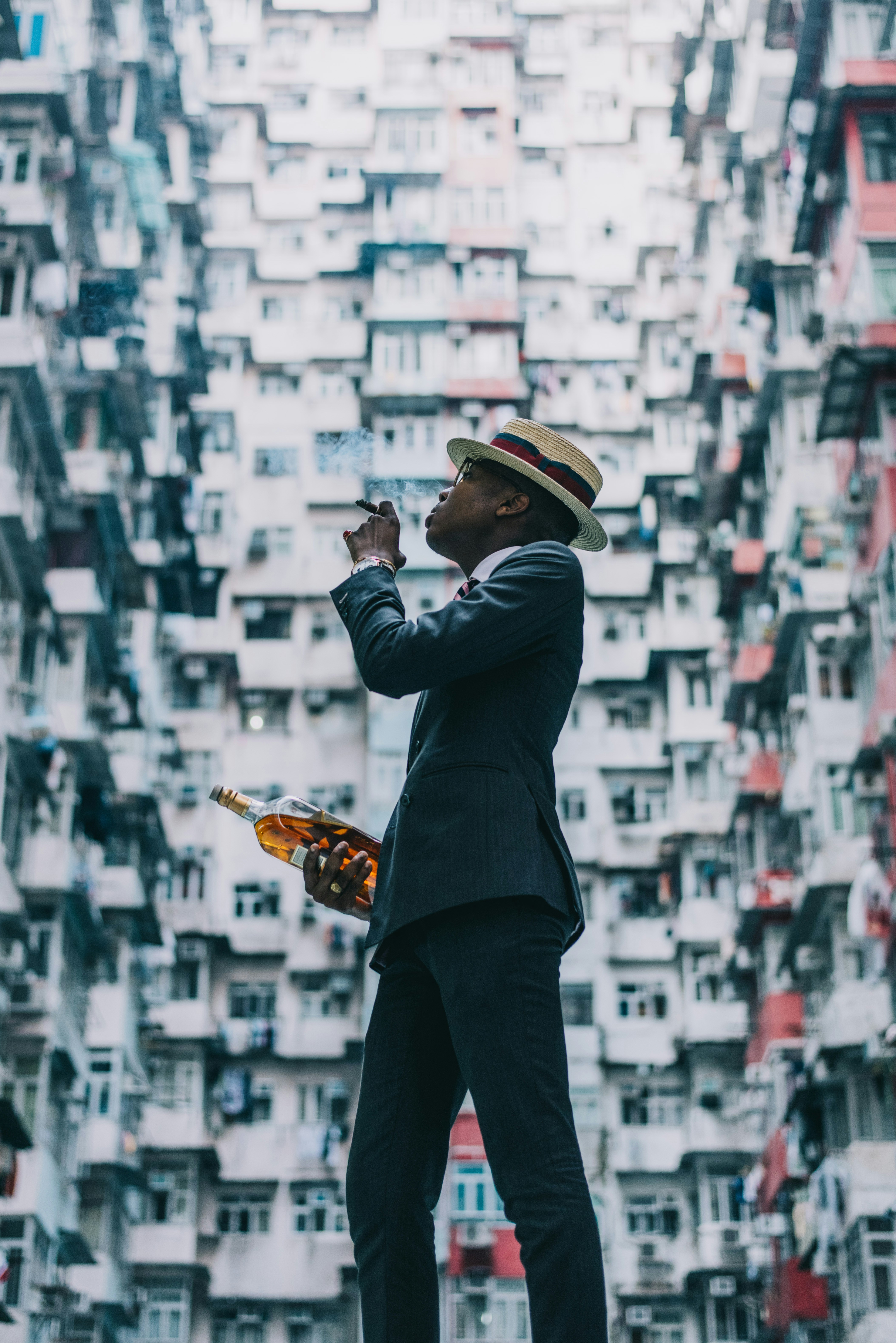 검은 양복 재킷과 검은 바지를 입은 남자가 금 트로피를 들고 있다