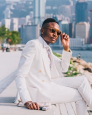 man in white suit sitting on concrete bench during daytime