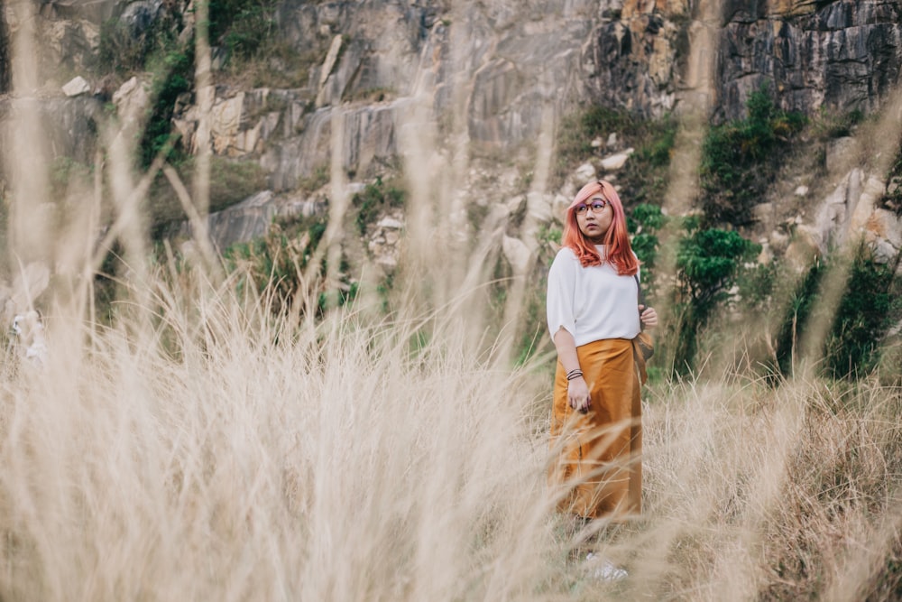 woman in white crew neck t-shirt and brown skirt standing on brown grass during daytime