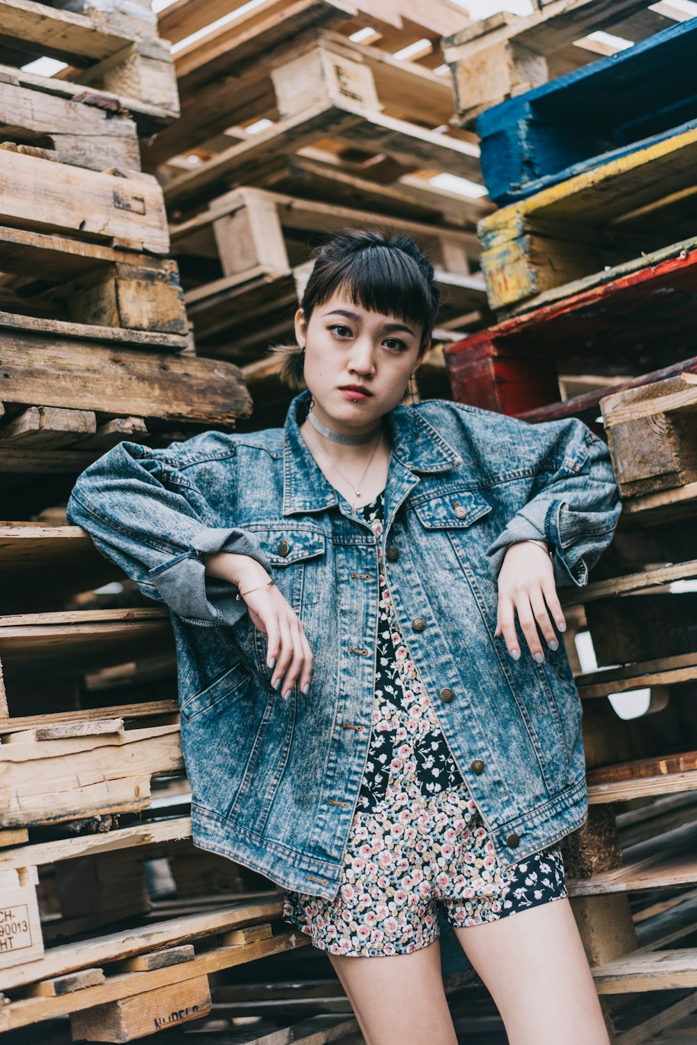 woman in blue denim jacket standing near brown wooden pallet