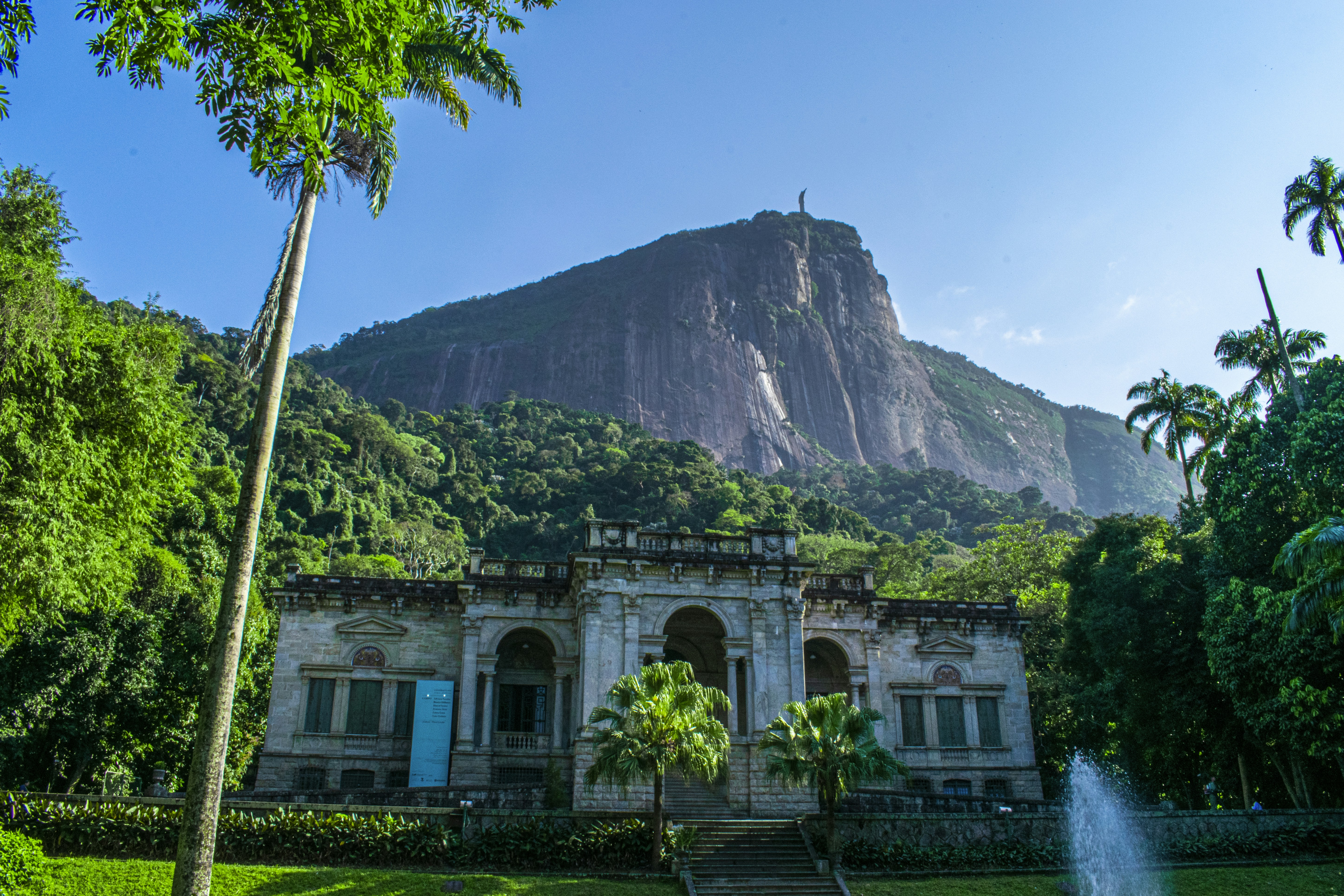 white concrete building near green trees and mountain during daytime
