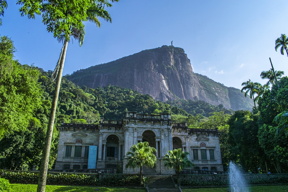 Edificio de hormigón blanco cerca de árboles verdes y montaña durante el día