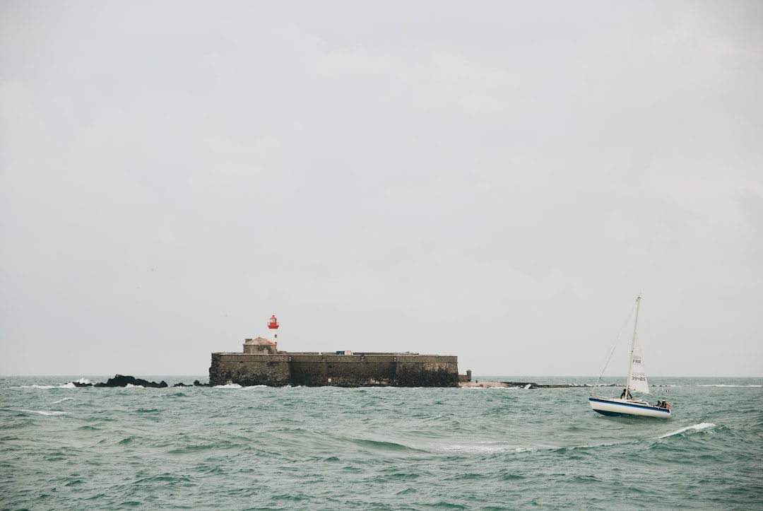 white sailboat on sea under white sky during daytime