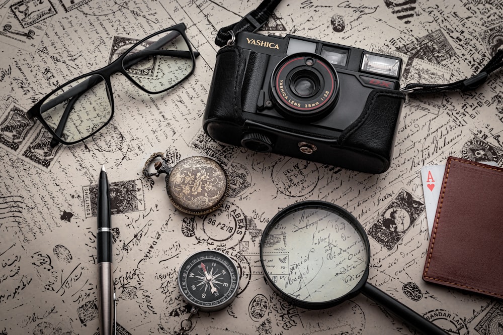 black nikon dslr camera beside black framed eyeglasses and black framed eyeglasses