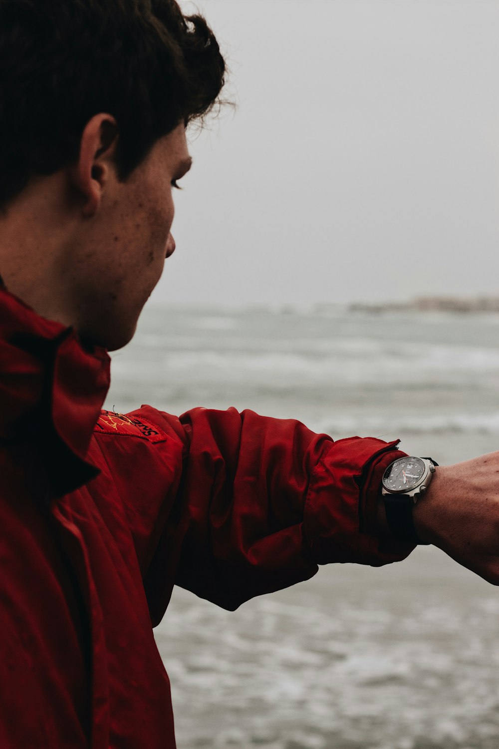 a man in a red jacket is flying a kite