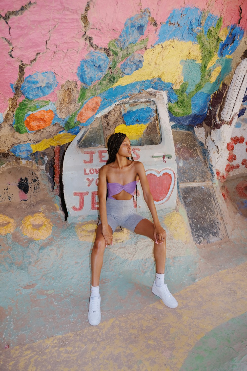 a woman sitting on the ground in front of a painted wall