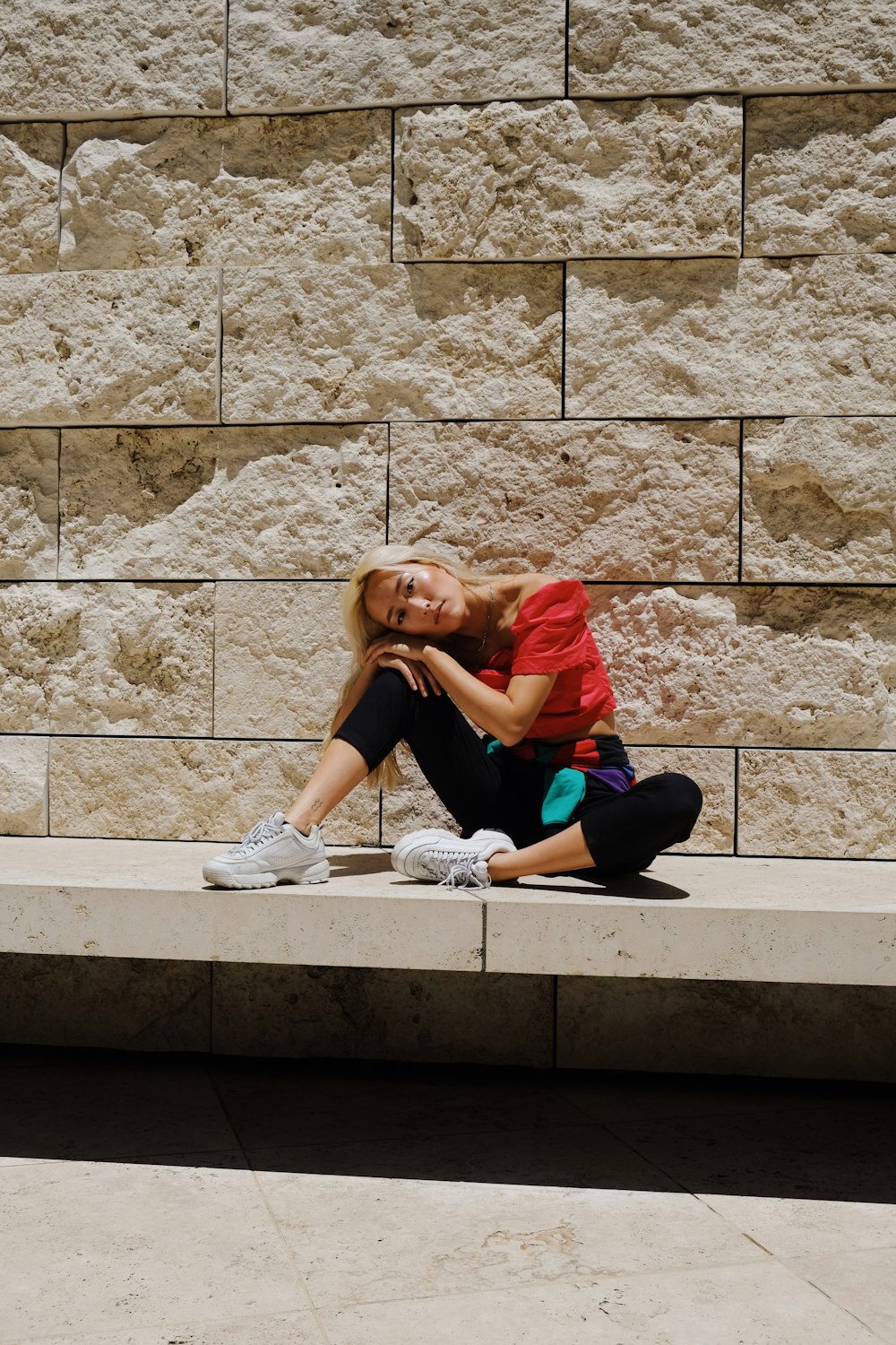 woman in red shirt and blue pants sitting on concrete stairs